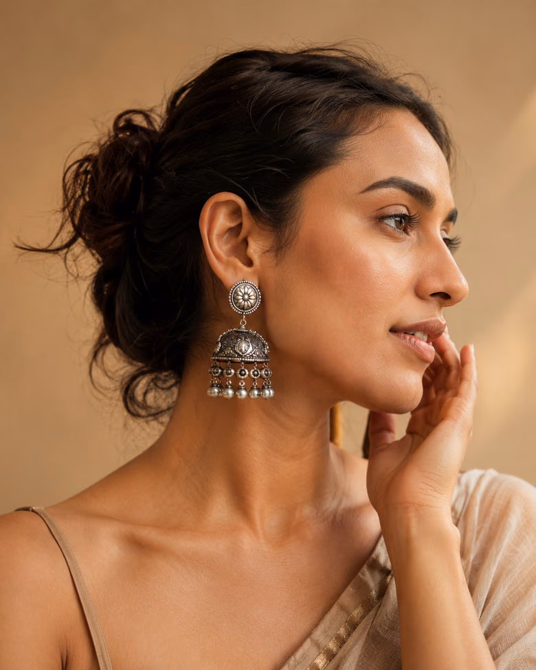 Woman in profile wearing ornate gold jhumka earrings.