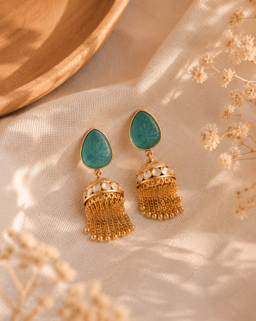 Teal Kundan Jhumkas with a carved teal stone and gold chain tassels.